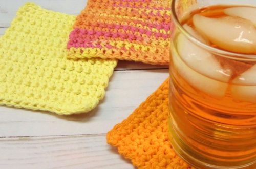 Three absolute beginner crochet coaster in orange, yellow, and orange ombre. Glass filled with ice and orange colored drink.