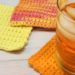 Three absolute beginner crochet coaster in orange, yellow, and orange ombre. Glass filled with ice and orange colored drink.