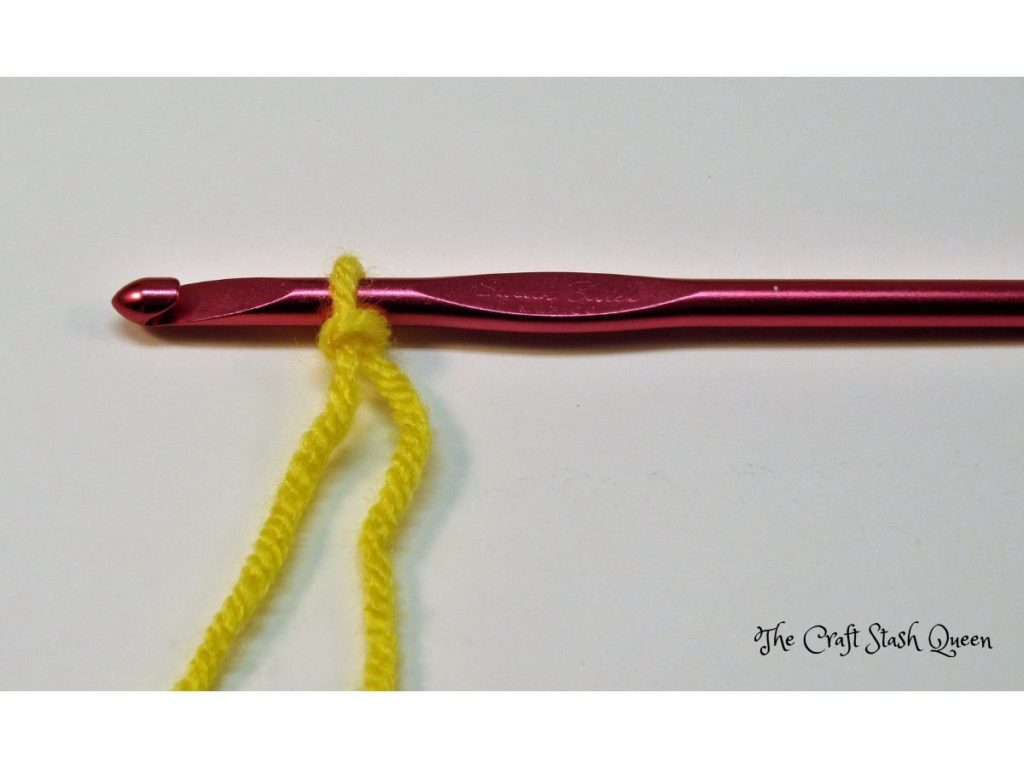 Yellow yarn tied into a slip knot placed on a crochet hook.