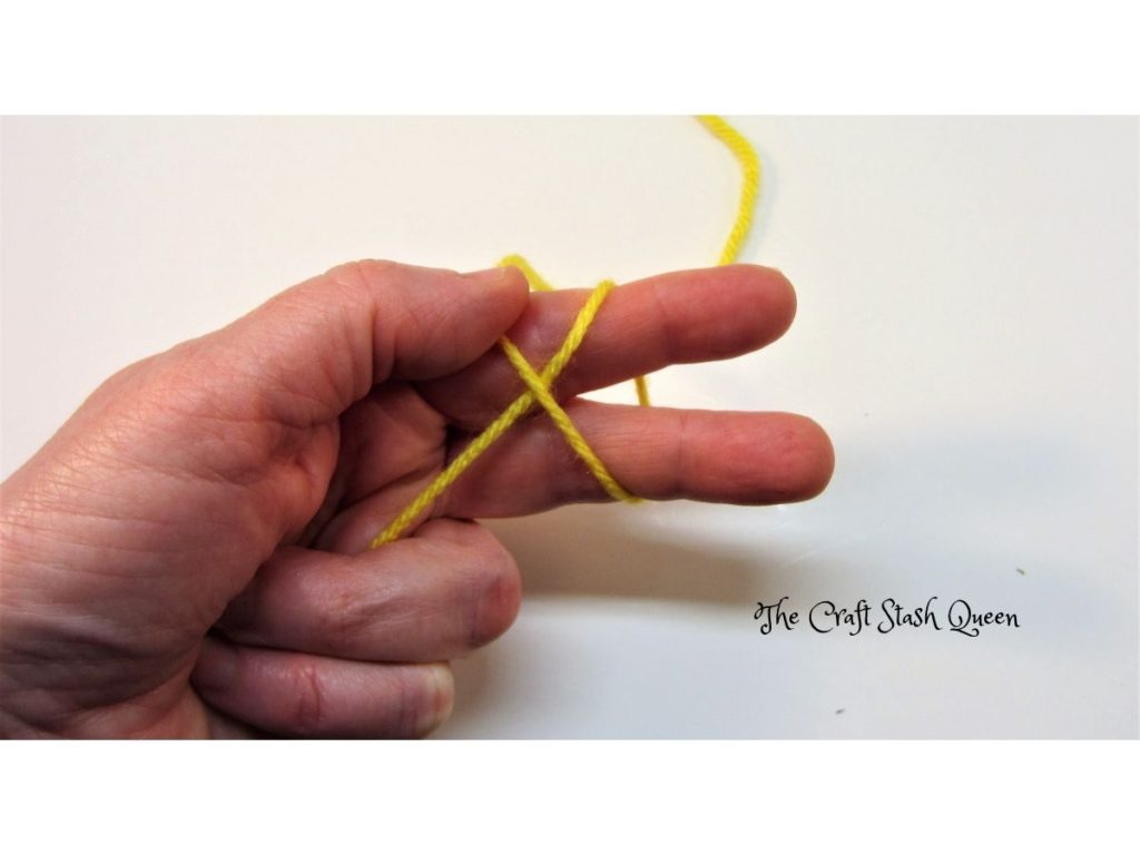Yarn wrapped around two fingers.  Yarn tail anchored by ring finger and little finger.  Working yarn anchored by thumb.