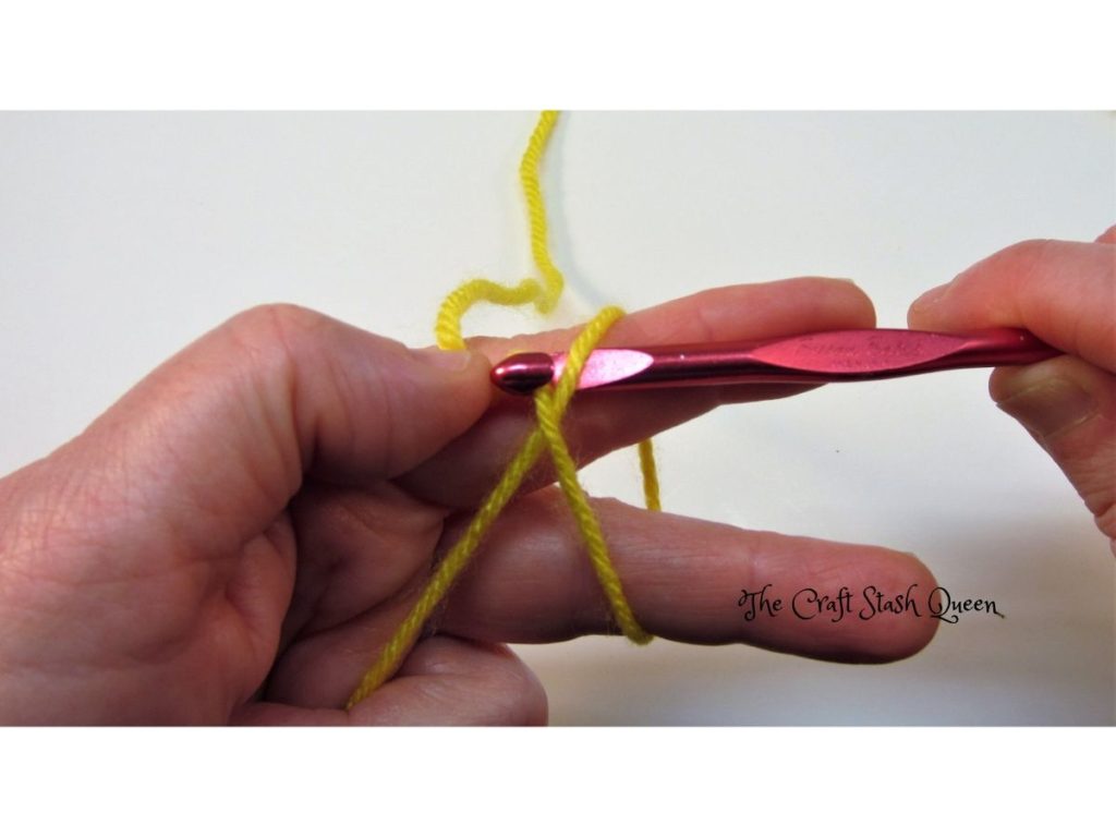Crochet hook hooking working yarn to make a slip knot.