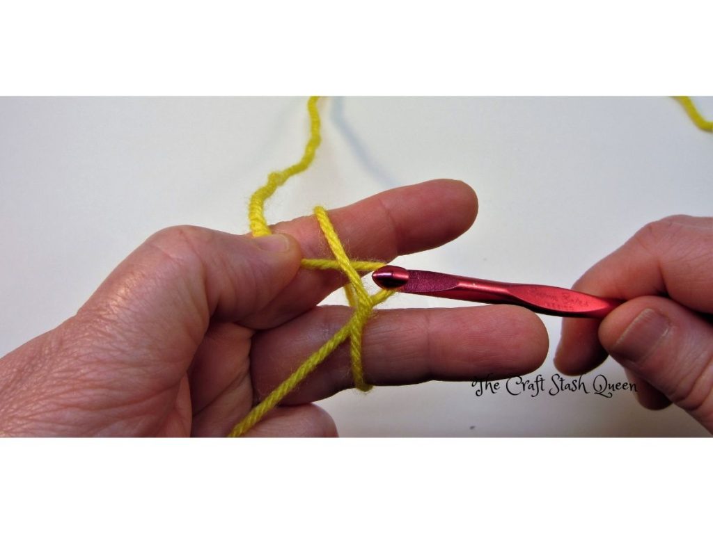 Crochet hook pulling  yarn through loop to make a slip knot.