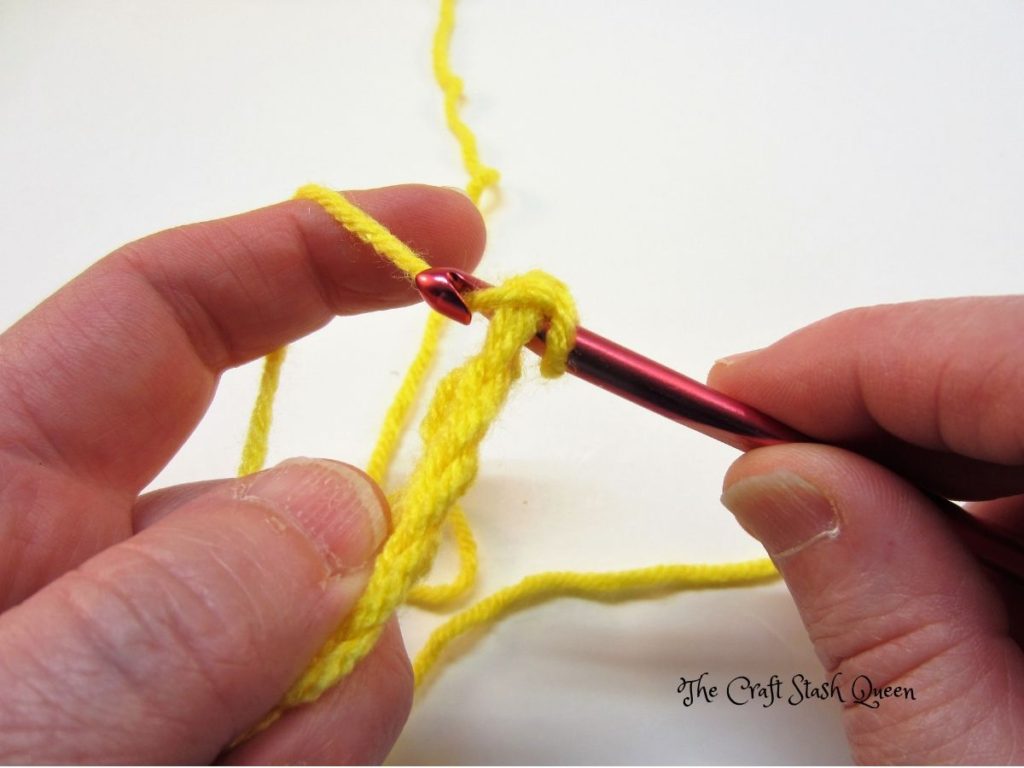 Example of yarn over.  Yellow yarn. Red crochet hook.