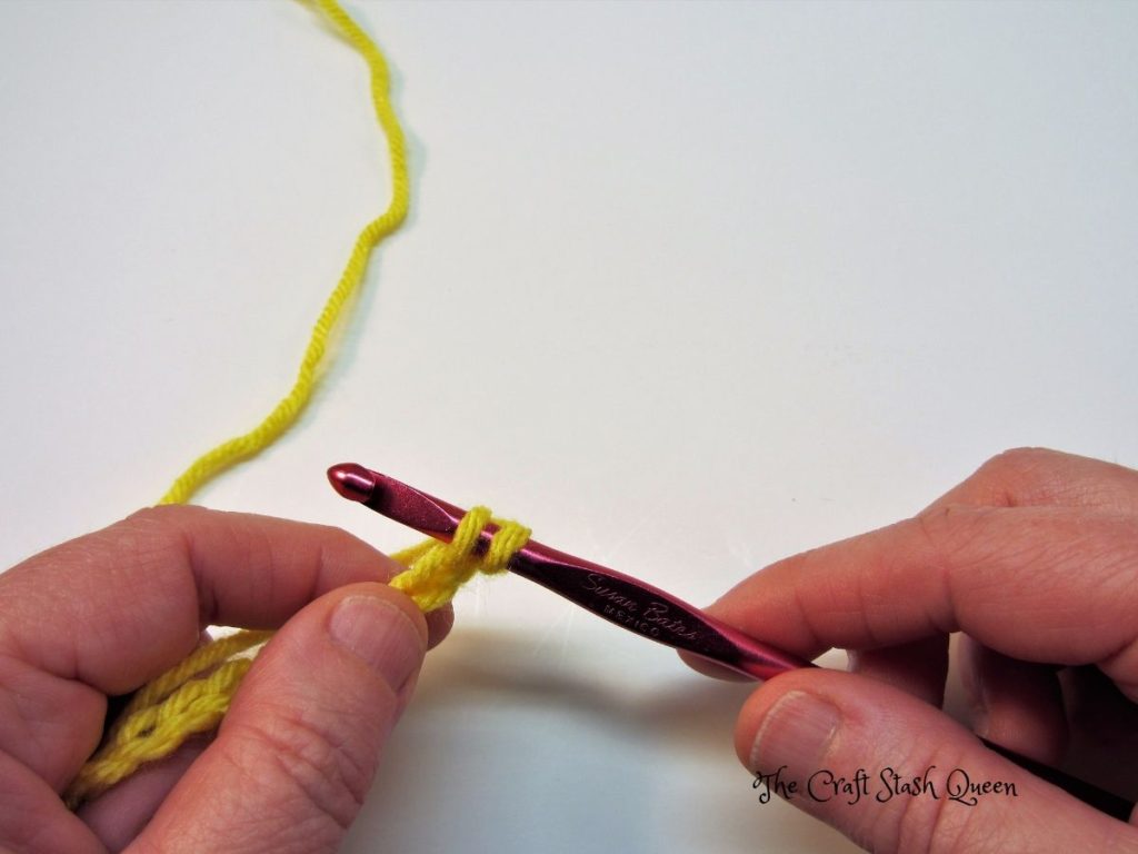 Red crochet hook with active loop on hook.  Hook is inserted into second chain from hook.