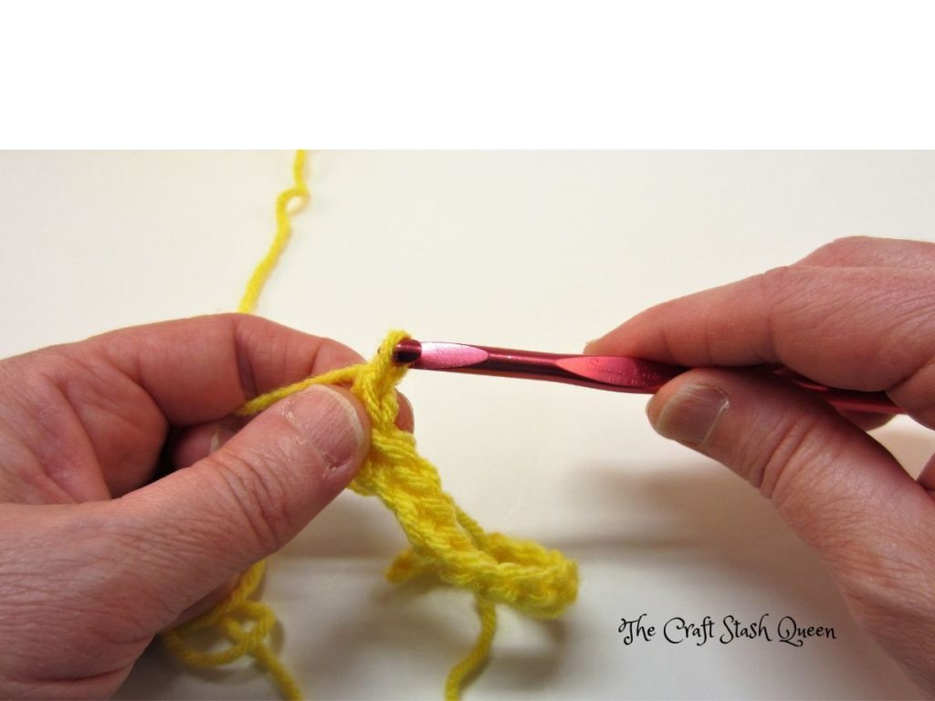 Yellow yarn.  Red crochet hook.  One row of single crochet.  Example of chain 1 at the end of a row.